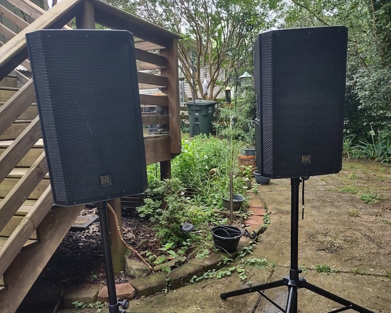 Two Electro-Voice ZLX-15BT 15-inch powered speakers on stands in a Nashville backyard